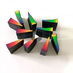 several pieces of art made out of black and multicolored wood sitting on a white surface