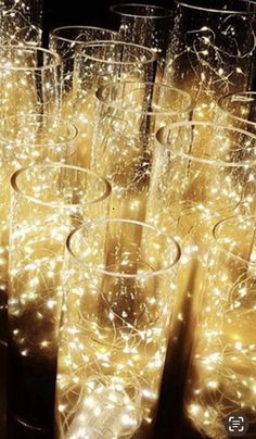 many champagne glasses are lined up in rows with lights all over the rims on them