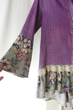 a woman's hand is holding up a purple blouse