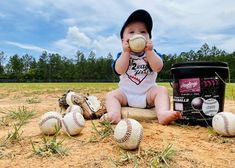 a baby is sitting in the sand with baseballs