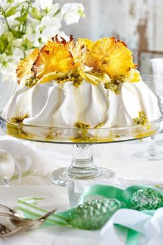 a white cake with yellow flowers on top is sitting on a glass platter next to other decorations