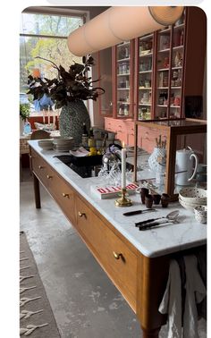 a kitchen counter with utensils on it in front of a potted plant