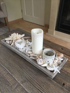 a candle and some seashells on a tray