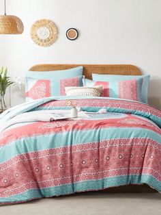 a bed with pink, blue and green bedspread on top of it in a room