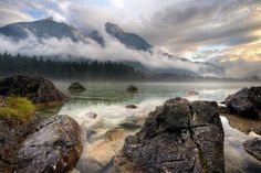 some rocks and water with mountains in the background