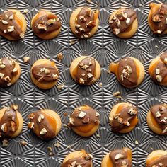 chocolate covered doughnuts are arranged on a baking sheet with nuts and other toppings