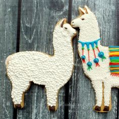 two decorated llamas sitting next to each other on top of a wooden fence