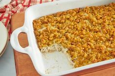 a casserole dish filled with food on top of a wooden cutting board next to a plate