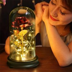 a woman sitting at a table next to a flower in a glass dome with lights