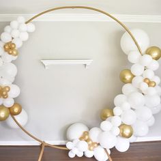 a white and gold balloon arch in the shape of a circle on a wooden floor