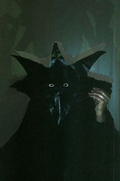 a person wearing a black cat mask in the dark