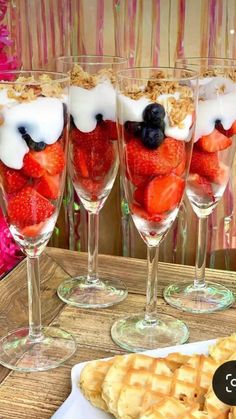 three glasses filled with strawberries on top of a table next to cookies and pie