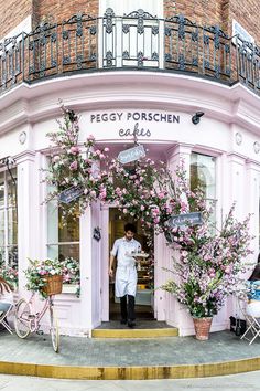 a man standing in front of a pink building with lots of flowers growing out of it