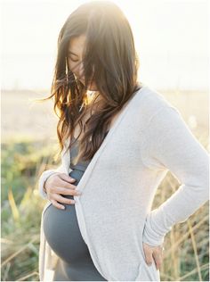 a pregnant woman is standing in the grass