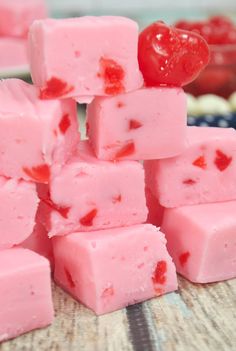 a pile of pink fudges sitting on top of a table next to a bowl of fruit