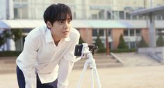 a young man looking at something on a tripod in front of a large building