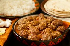 meatballs and rice in a bowl on a table with other food items including pita bread