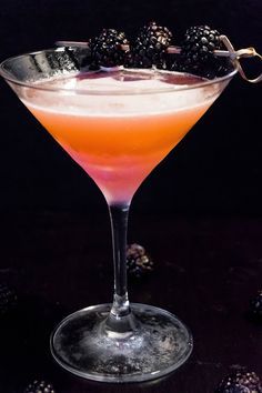 a pink martini with blackberries on the rim