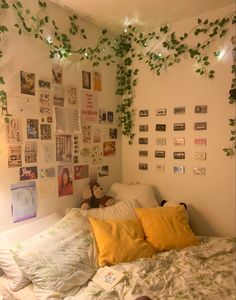 an unmade bed with lots of plants growing on the wall above it and stuffed animals hanging from the ceiling