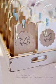 small bags with horses on them are sitting in a wooden box and tied to string