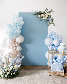 blue and white balloons are on display in front of a large balloon arch with flowers