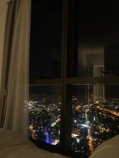 a view from a window at night looking down on the city lights and skyscrapers