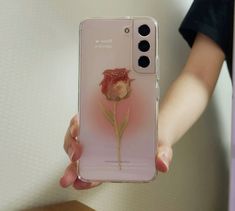 a person holding up a pink phone case with a flower on the front and side