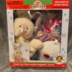 a white stuffed animal in a box with other items inside it, including a pink bunny and snowflakes