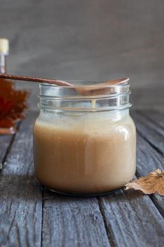 a jar filled with liquid sitting on top of a wooden table next to a maple leaf