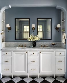 a bathroom with two sinks and mirrors in the wall, along with an arched doorway leading to another room