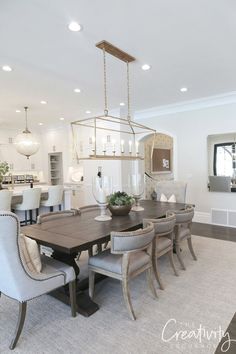 a dining room table with chairs and a chandelier hanging from the ceiling above it