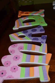 colorful wooden letters are lined up on the table with flowers and stripes painted on them