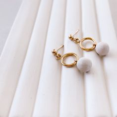 Dot Earrings offer a simple and elegant open circle design that adds a touch of minimalism to your everyday style. The sculpted porcelain charm dangles delicately, creating movement as you wear them. Crafted with care, these earrings are made from 100% 14-karat gold-fill, ensuring both style and durability. Sold as a pair. Minimalist Small Hoop White Jewelry, Dot Earrings, Everyday Chic, Gold Piece, Gold Shimmer, Vases And Vessels, Circle Design, 22k Gold, Everyday Style