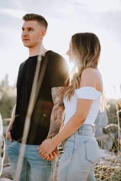 a man and woman standing next to each other in front of some rocks with the sun shining on them