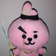 a pink teddy bear holding a toothbrush in its mouth and wearing a gold chain around it's neck