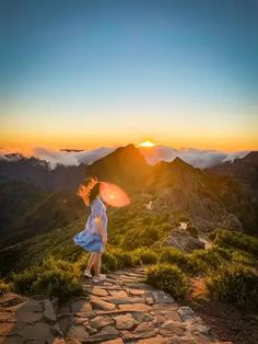 a woman walking up a stone path at sunset