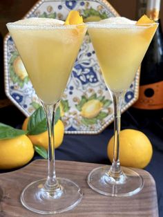 two glasses filled with lemonade sitting on top of a wooden table