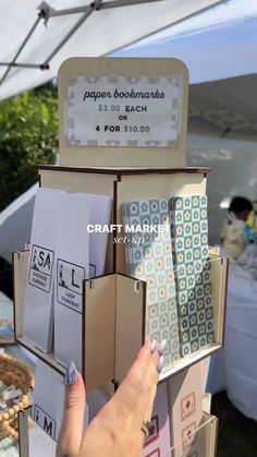 a person is holding up some books at an outdoor book sale in front of a tent