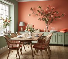 a dining room with an orange wall and wooden table surrounded by wicker chairs in front of it