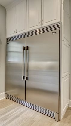 a stainless steel refrigerator in a kitchen with white cabinets