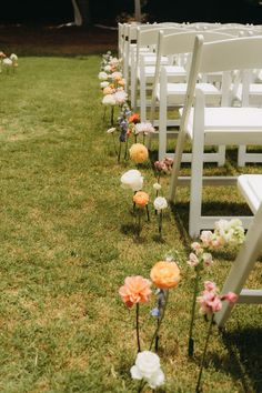 rows of white chairs with flowers on the grass