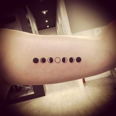 a woman's arm with five phases on the left side of her body and four black dots in the middle