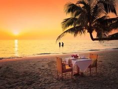 a table set up on the beach for two people to enjoy at sunset or dinner