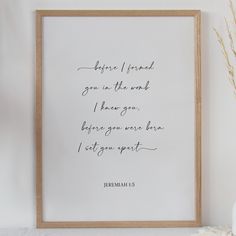 a framed print with a quote on it sitting next to a vase and some dried flowers