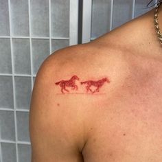 a woman with a tattoo on her shoulder that has two horses running across the chest