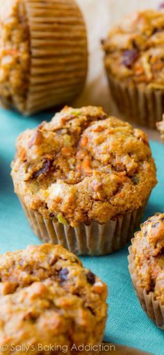 several carrot muffins sitting on top of a blue cloth next to other muffins