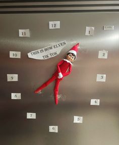 an elf is hanging on the side of a wall with numbered numbers and a sign that says, this is how elves tik tok