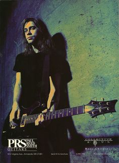 a man with long hair playing an electric guitar in front of a blue wall,