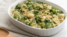 broccoli and cauliflower casserole in a white dish with a wooden spoon