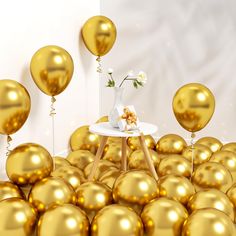 a vase with flowers on a table surrounded by golden balloons